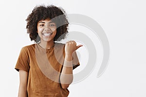 Waist-up shot of friendly good-looking optimistic dark-skinned teenage girl with afro hairstyle in stylish brown t-shirt