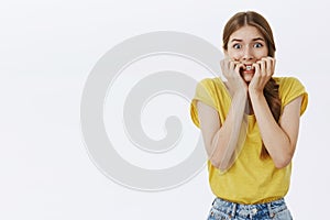 Waist-up shot of girl about panic feeling frightened and concerned biting fingers from anxiety and worry popping eyes at