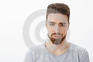Waist-up shot of handsome sensual and confident young man with beard, moustache and blue eyes smiling looking sincere