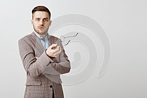 Waist-up shot of intense confused good-looking male entrepreneur in stylish jacket taking off glasses and gesturing with