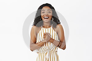 Waist-up shot of pleased and delighted happy young african american successful businesswoman in elegant striped yellow