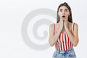 Waist-up shot of shocked girlfriend standing in stupor over grey background dropping jaw gasping from worry and shock