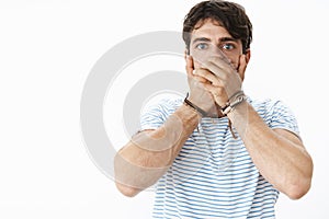 Waist-up shot of shocked panicking handsome insecure guy feeling anxious, overthinking, acting immature covering mouth