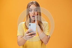 Waist-up shot of shocked and stunned emotive young woman reacting to shocking terrible news reading online from internet
