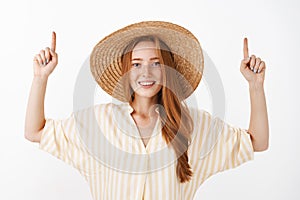 Waist-up shot of sociable and communicative good-looking stylish redhead woman in yellow stylish blouse and straw hat