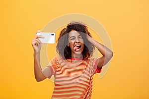 Waist-up shot of stylish confident african american woman with afro hairstyle in trendy t-shirt taking selfie on awesome