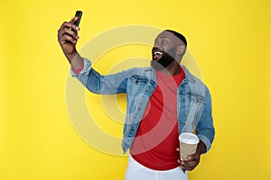 Waist up of smiling African man keeping cupholder and smartphone in arms