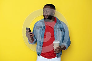 Waist up of smiling African man keeping cupholder and smartphone in arms