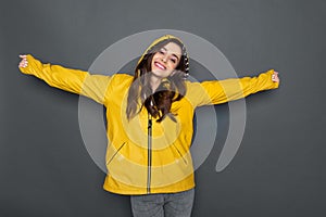 Waist up of smiling Caucasian girl dressed in yellow raincoat in studio