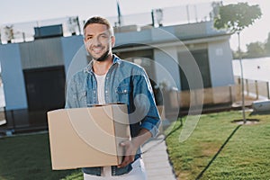 Waist up of a pleasant man holding a paper box