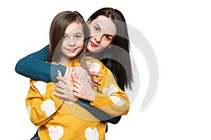 Waist up studio portrait of a beautiful young mother embracing her daughter. Happy smiling family background.