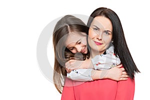 Waist up studio portrait of cute and playful schoolgirl embracing her mother. Happy family smiling background isolated.