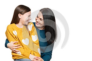 Waist up studio portrait of a mother and young daughter face to face laughing. Happy family laughing background.
