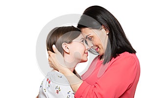 Waist up studio portrait of a young mother embracing her cute schoolgirl daughter. Happy smiling family background.