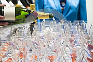 Waiter bartender pouring white wine into glasses at party event