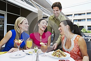 Waiter Bringing Check to Women In Restaurant