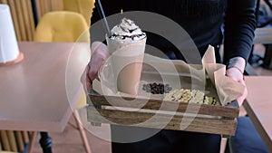 Waiter carries the order to the client Irish coffee served with waffles on a tray. Hands close-up.