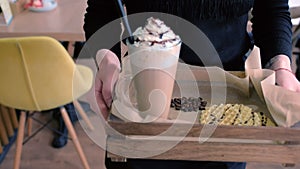 Waiter carries the order to the client table Irish coffee served with waffles on a tray. Hands close-up.