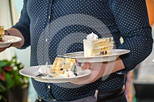 Waiter carries plates with desserts of cakes