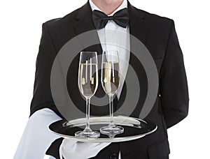 Waiter carrying champagne flutes on tray photo