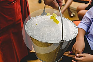 Waiter carrying a metal bucket full of ice to cool drinks in summer