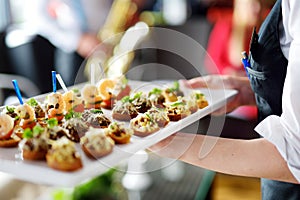 Waiter carrying plates with meat dish on festive event, party or wedding reception