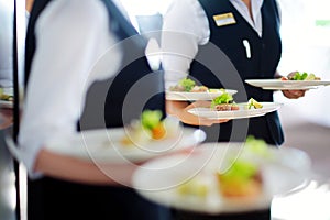 Waiter carrying plates with meat dish on some festive event
