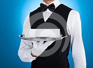 Waiter carrying silver tray with blank card