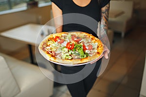 Waiter carrying two different plates with a tasty pizza. Photo with two pizza. Pizza with mushrooms and pizza with salami. Italian