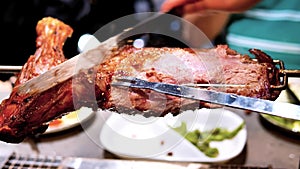 Waiter cuts roasted lamb leg for customer in restaurant, delicious food, 4k movie, slow motion