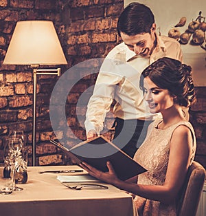 Waiter explaining the menu to a beautiful woman