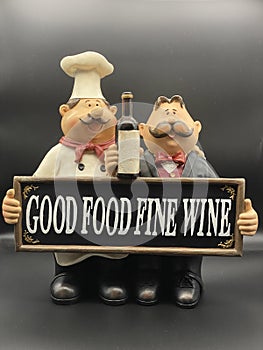 And waiter figurines holding good food fine wine sign on black background