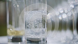 Waiter filling empty glass with champagne near glass of sparkling water.