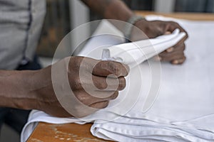 Waiter folds napkins in restaurant. Waiters hands with white napkin closeup