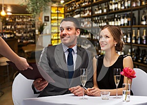 Waiter giving menu to happy couple at restaurant