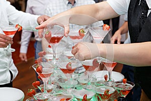 Waiter hand with glass of champagne over pyramid during catering at party