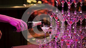 Waiter hand with glass of champagne over pyramid during catering at party. Clip. Pyramid of glasses of champagne