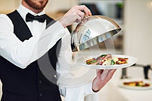 Waiter, hands and opening plate of food for serving, meal or customer service at indoor restaurant. Man employee caterer