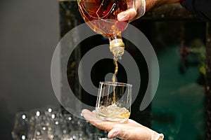 Waiter hands pouring drink from a glass.