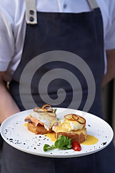 Waiter holding breakfast tray with Eggs Benedict
