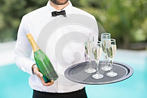 Waiter holding champagne flutes and bottle