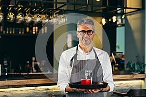 Waiter holding coffee and water on plate in cafe bar
