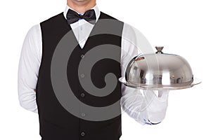 Waiter holding metal cloche lid cover on tray