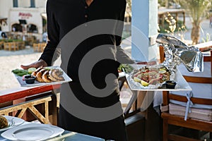 Waiter is holding plates with ready-made dishes in his hands