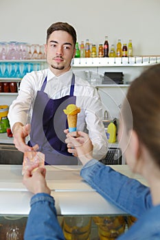 Waiter holding scoop and bowl in ice cream parlor