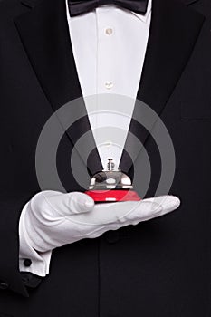 Waiter holding a service bell.