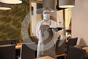 Waiter holding tray with beverages in restaurant. Catering during coronavirus quarantine