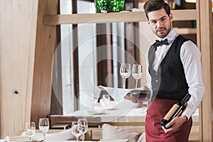 Waiter holding wineglasses and bottle