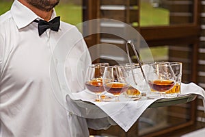 The waiter holds a tray with alcohol