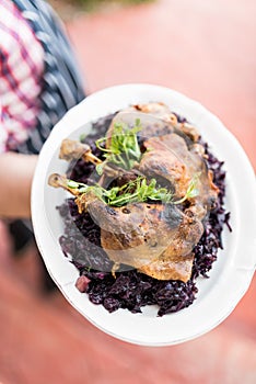 Waiter with large platter- duck confit and wine braised cabbage